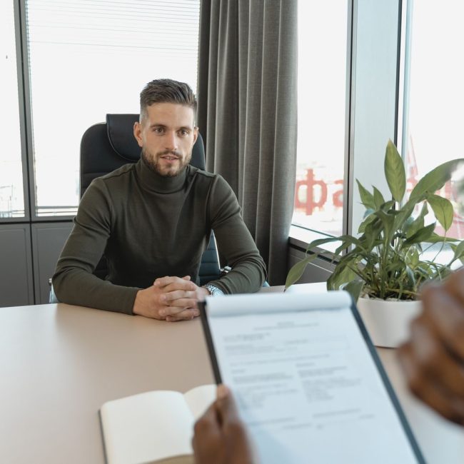 Professional man in turtleneck at office desk during an interview.