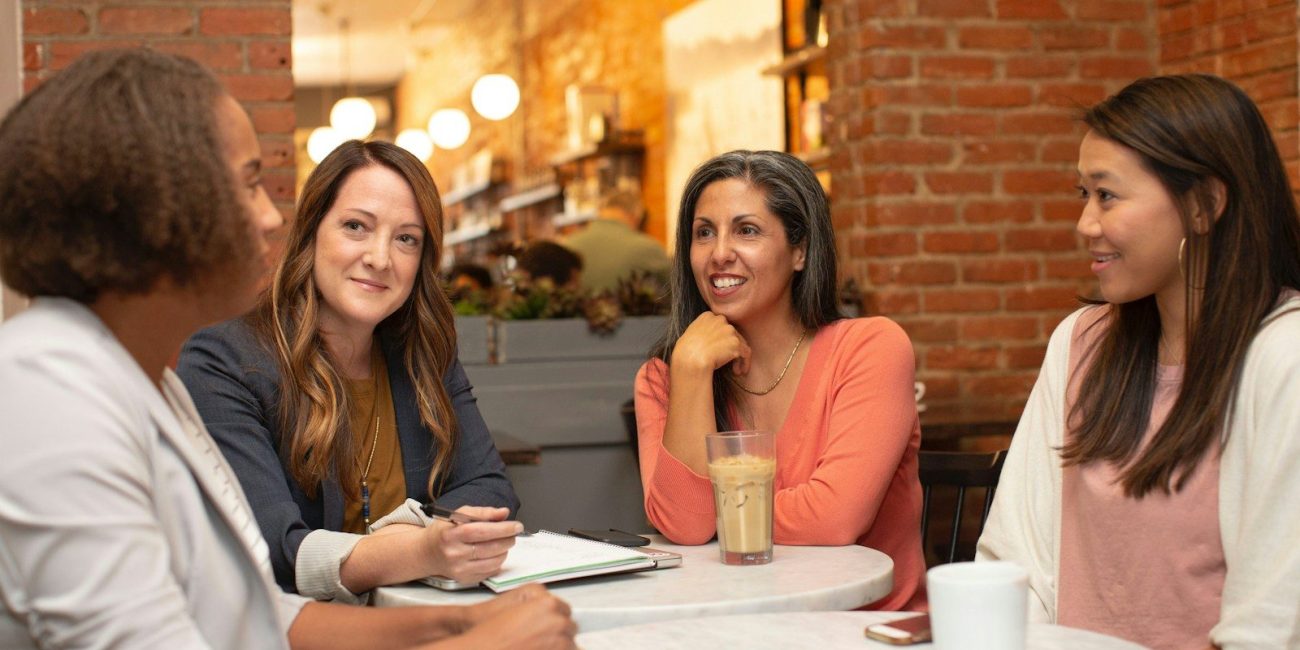 four women chatting at cafe table