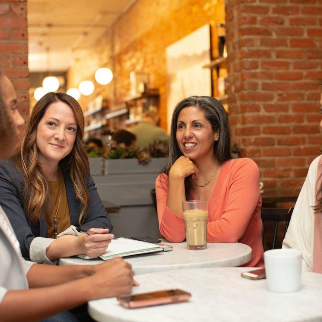 four women chatting at cafe table